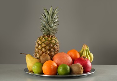 Photo of Plate with different ripe fruits on grey table