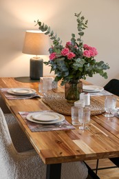 Photo of Beautiful table setting with bouquet and candles indoors. Roses and eucalyptus branches in vase