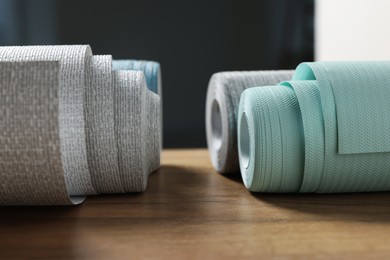 Photo of Different wallpaper rolls on wooden table indoors, closeup