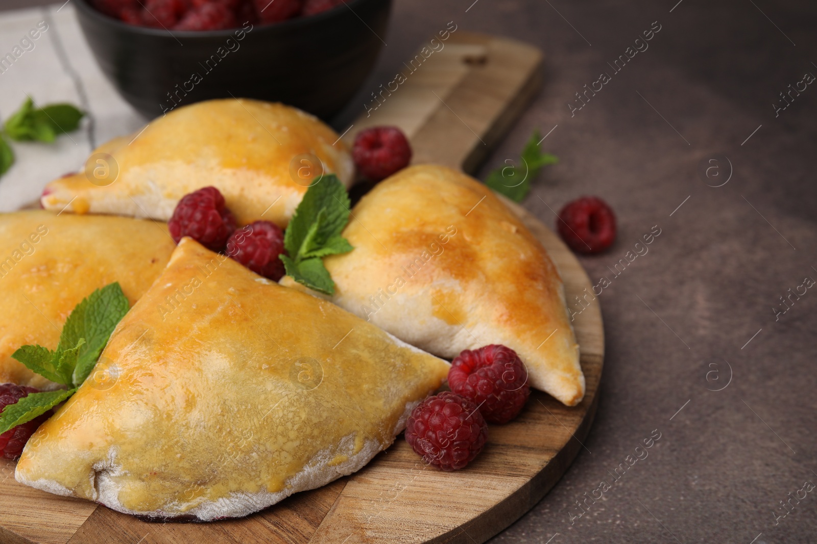 Photo of Delicious samosas with raspberries on grey table, closeup