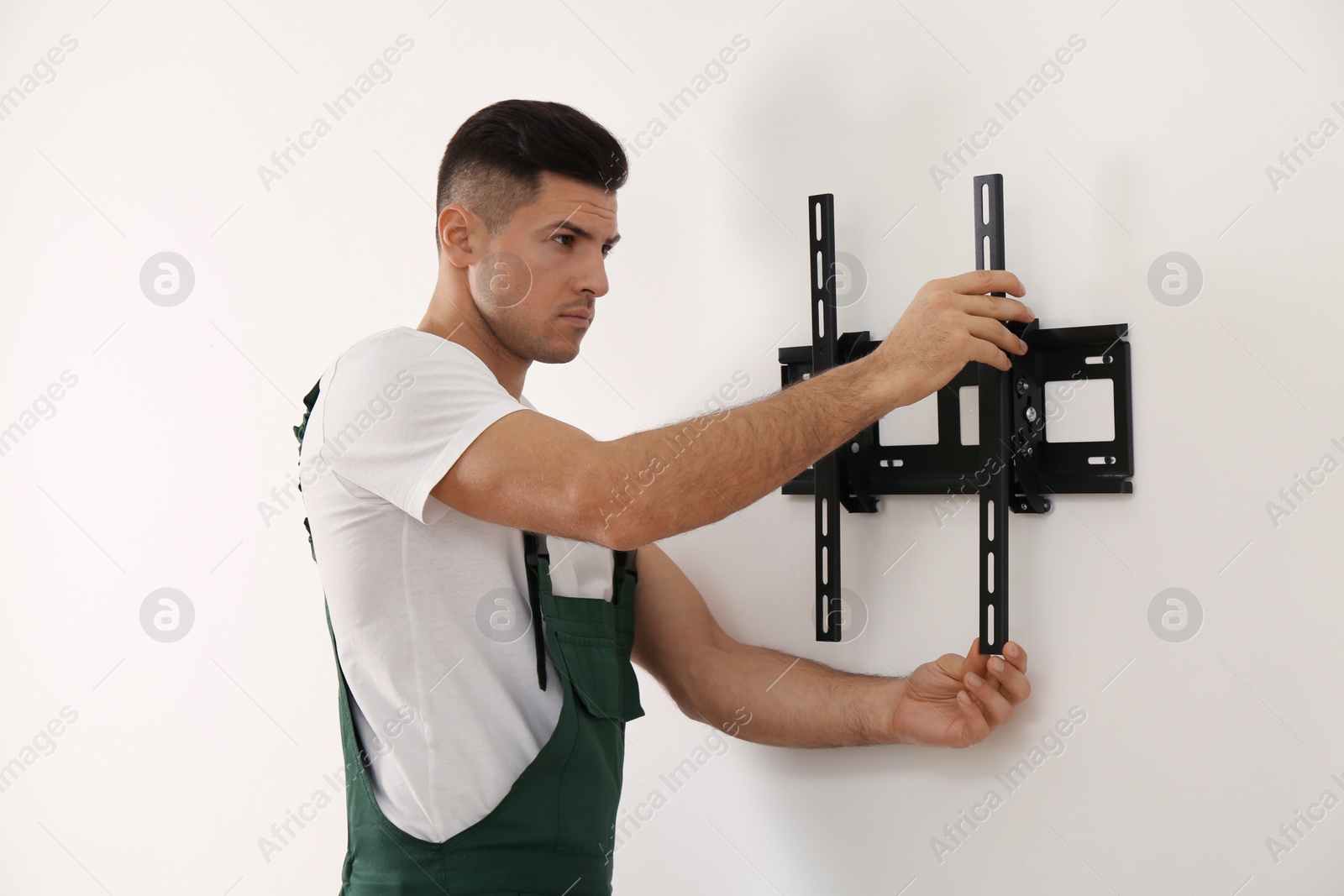 Photo of Professional technician installing TV bracket on wall indoors