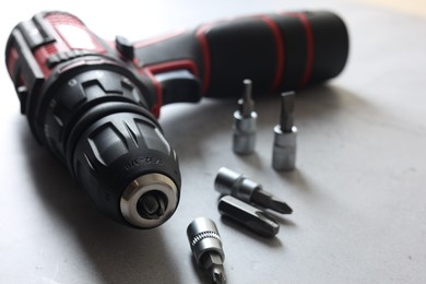 Modern electric screwdriver and bits on grey table, closeup