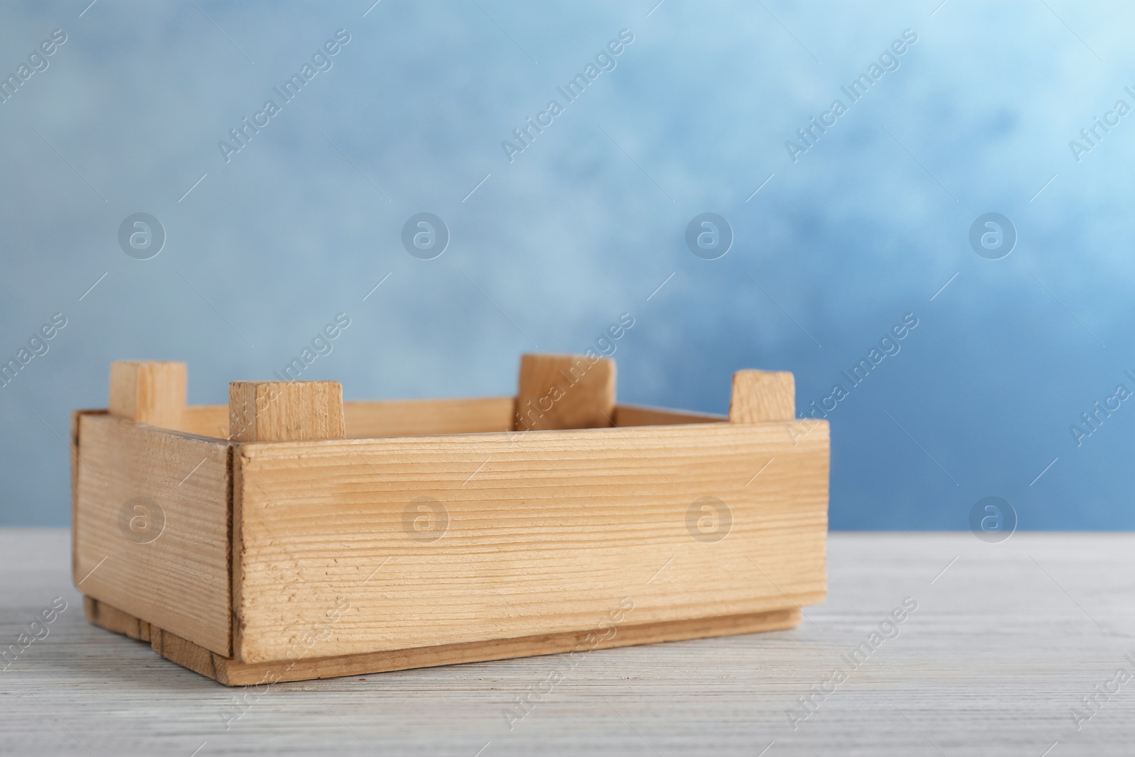 Photo of Wooden crate on table against color background. Space for text