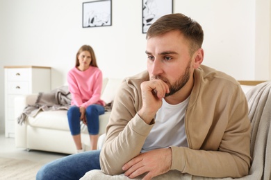 Photo of Young couple ignoring each other after argument in living room. Relationship problems