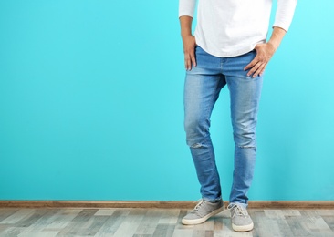 Photo of Young man in stylish jeans near color wall