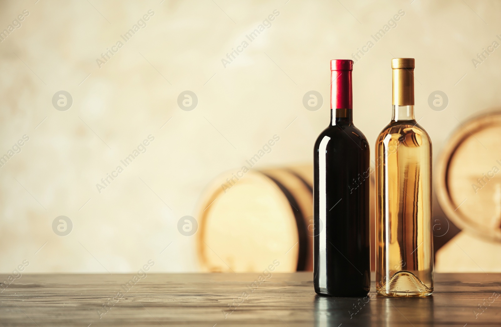 Photo of Bottles of delicious wine and blurred barrels on background