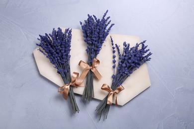 Photo of Bouquets of beautiful preserved lavender flowers and stone board on light grey textured table, top view