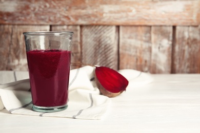 Glass of tasty beet smoothie on table with space for text