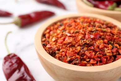 Photo of Chili pepper flakes in bowl on table, closeup