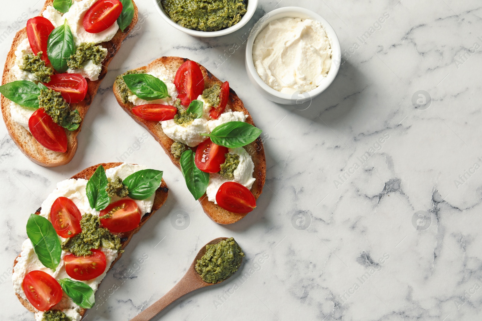 Photo of Toasted bread with tasty cream cheese and tomatoes on marble table, flat lay. Space for text