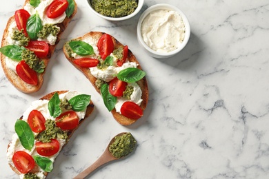 Photo of Toasted bread with tasty cream cheese and tomatoes on marble table, flat lay. Space for text