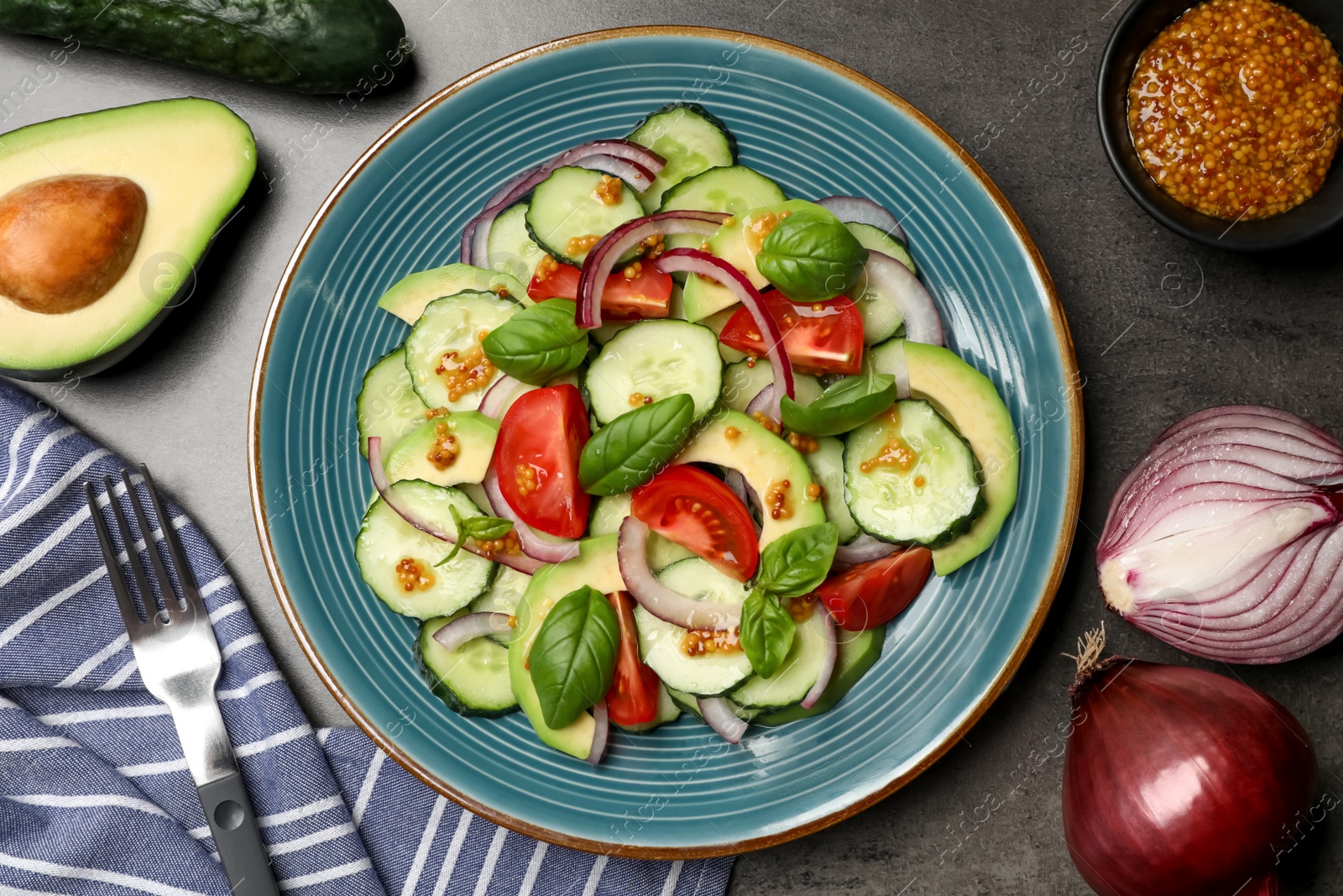 Photo of Tasty salad with cucumbers served on grey table, flat lay