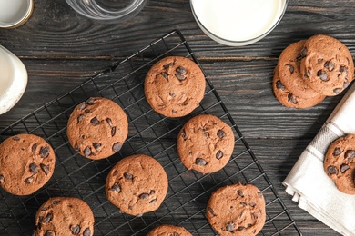 Cooling rack with chocolate chip cookies on wooden background, flat lay