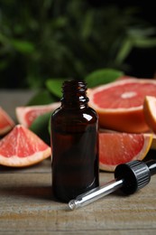 Photo of Citrus essential oil and grapefruits on wooden table