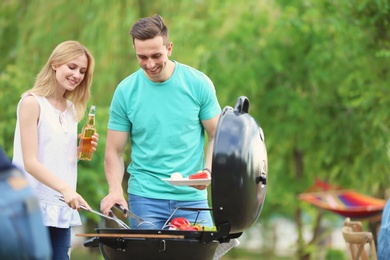 Young people having barbecue with modern grill outdoors