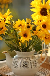 Photo of Beautiful flowers in teapot on table, closeup. Autumn atmosphere
