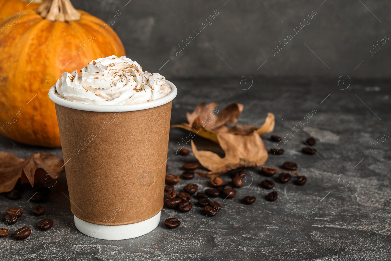 Photo of Paper cup with tasty pumpkin spice latte on grey table. Space for text