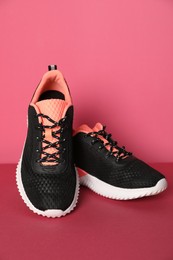 Photo of Pair of stylish sport shoes on pink background