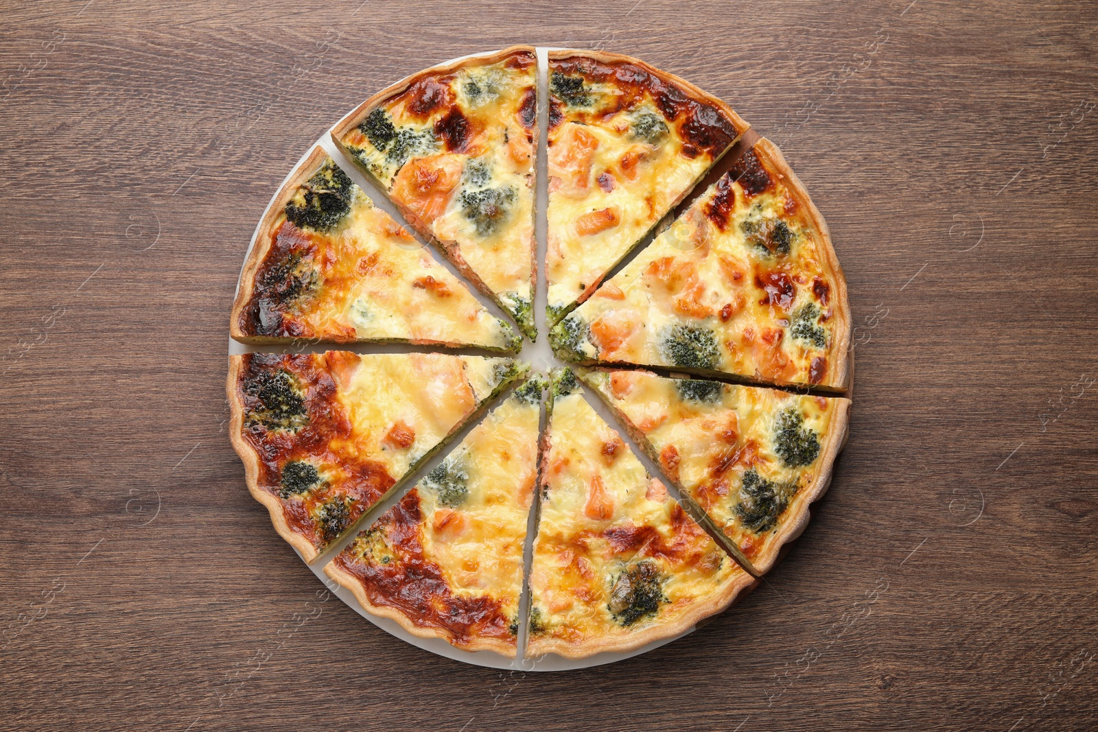 Photo of Delicious homemade quiche with salmon and broccoli on wooden table, top view