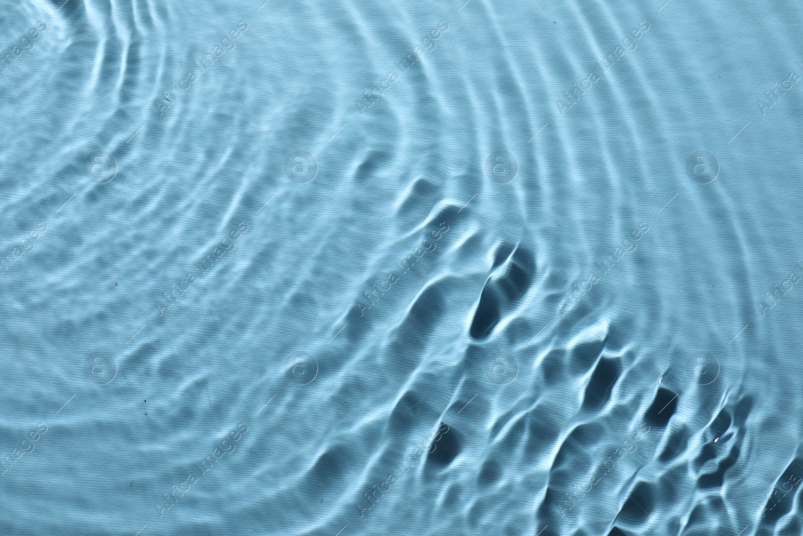 Photo of Rippled surface of clear water on light blue background, top view