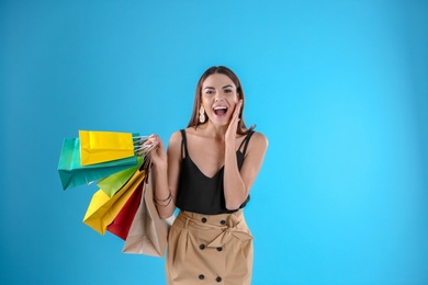 Photo of Young woman with shopping bags on color background. Space for text