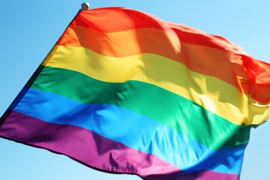 Rainbow LGBT flag fluttering on blue sky background. Gay rights movement