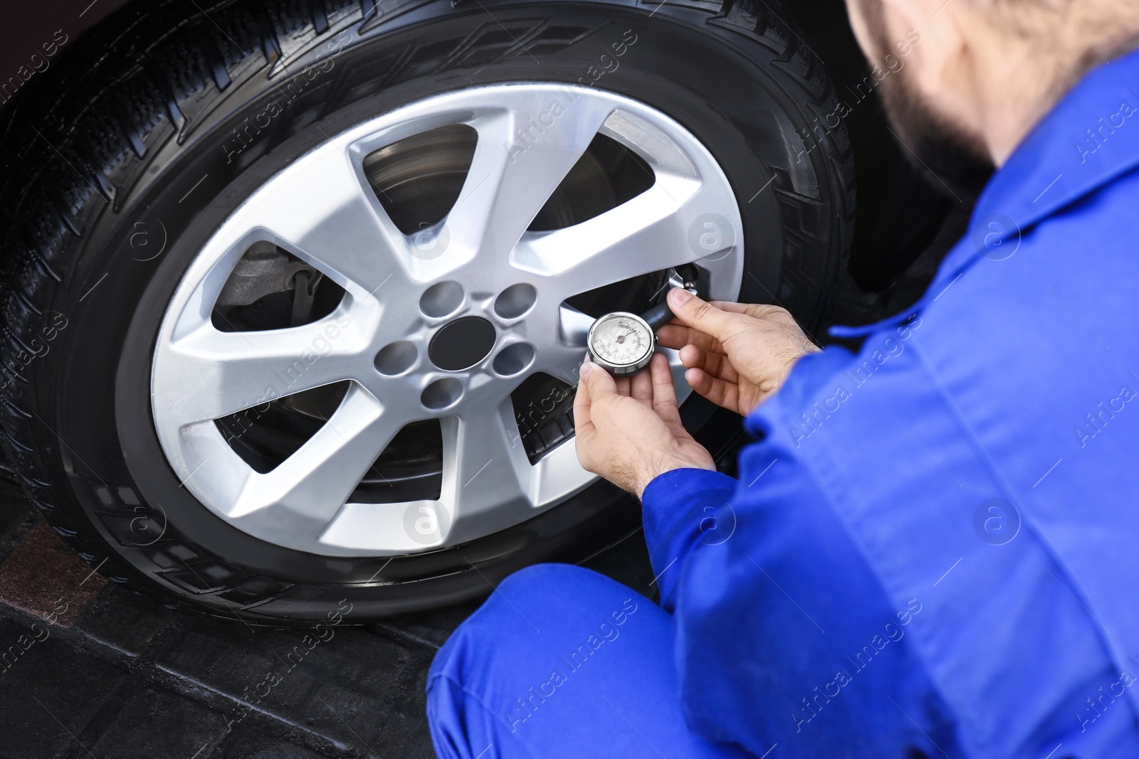 Photo of Mechanic checking tire air pressure at car service, closeup