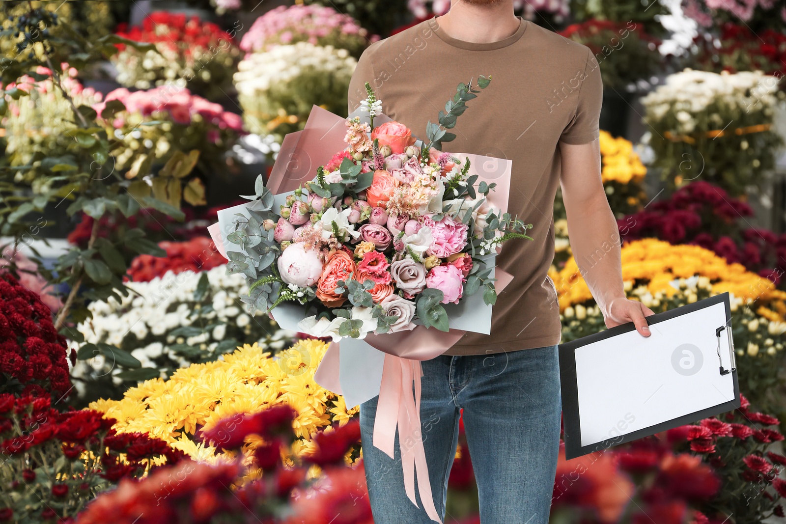 Image of Delivery man with beautiful bouquet in flower shop, closeup