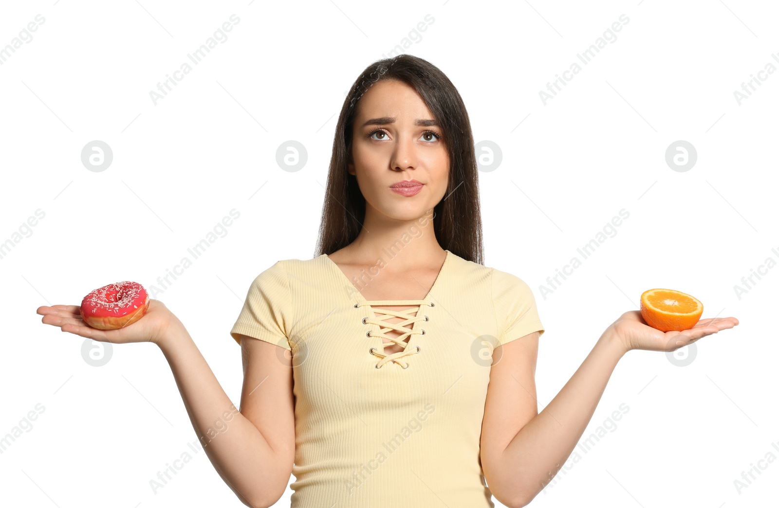 Photo of Doubtful woman choosing between orange and doughnut on white background