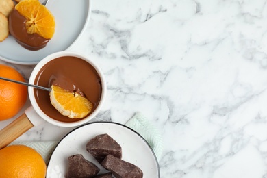 Photo of Flat lay composition with fondue pot and chocolate on white marble table, space for text