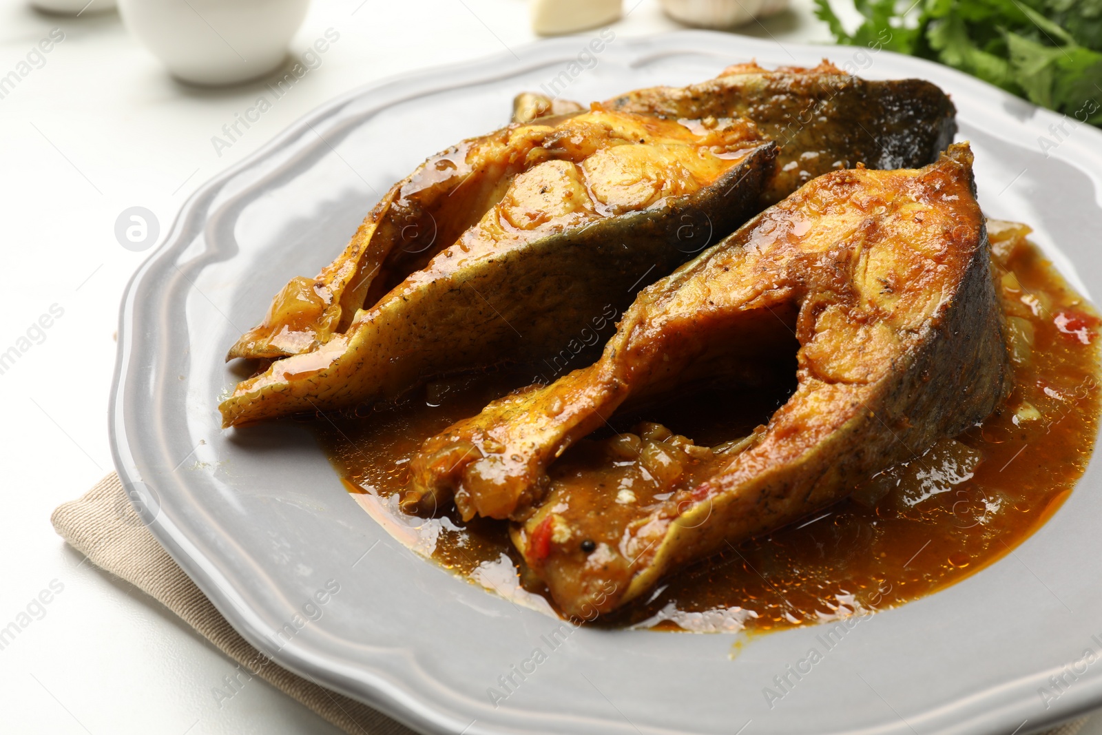 Photo of Tasty fish curry on white table, closeup. Indian cuisine