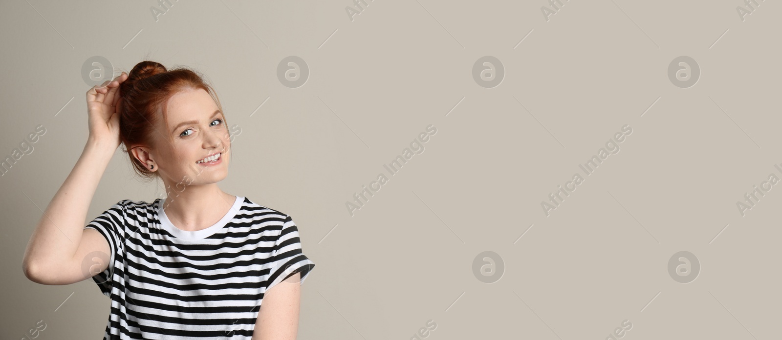 Photo of Candid portrait of happy red haired woman with charming smile on beige background, space for text