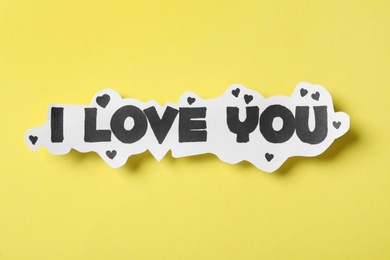 Card with text I Love You on yellow background, top view