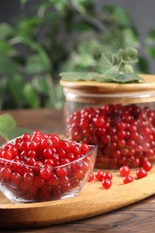 Photo of Ripe red currants and leaves on wooden table