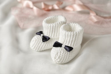 Photo of Handmade baby booties with bows on light plaid