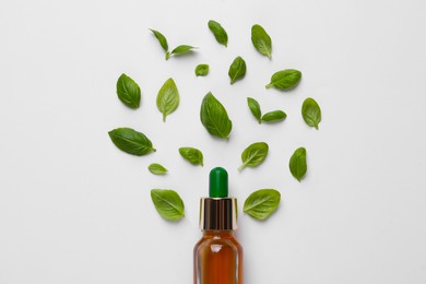 Photo of Bottle of essential basil oil and fresh leaves on white background, flat lay