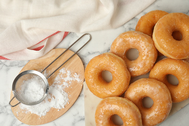 Delicious glazed donuts on marble table, flat lay