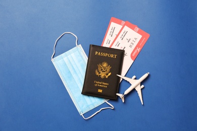 Photo of Flat lay composition with passport and protective mask on blue background. Travel during quarantine