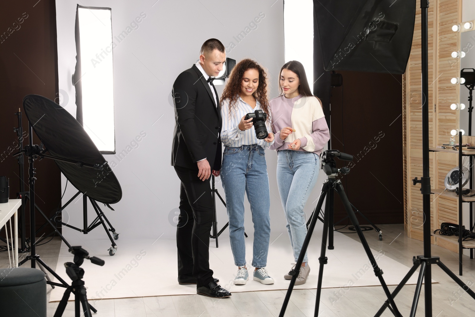 Photo of Professional photographer and makeup artist with model in studio