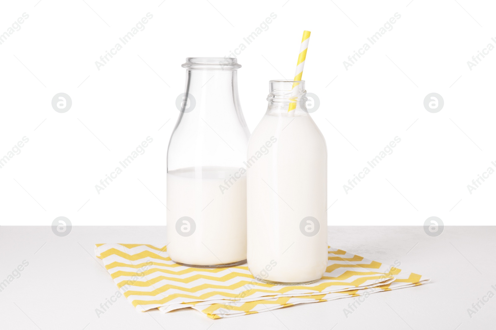 Photo of Bottles with tasty milk on light table against white background