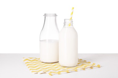 Bottles with tasty milk on light table against white background