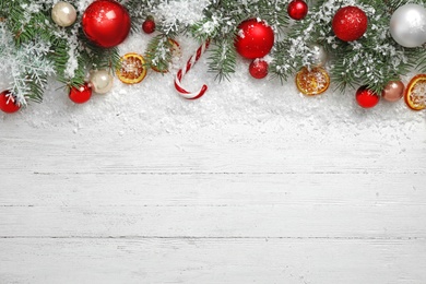 Photo of Christmas decoration with snow on white wooden background, flat lay. Space for text