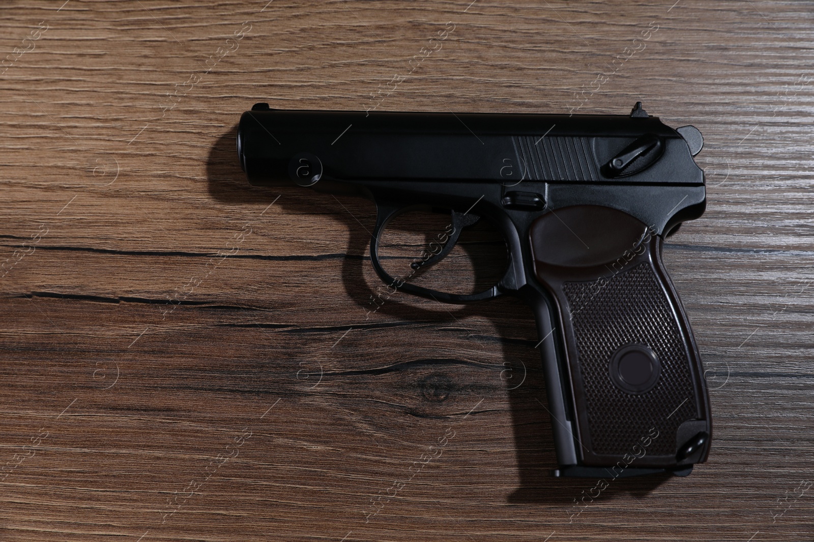 Photo of Handgun on wooden table, top view. Semi-automatic pistol