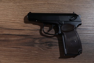 Photo of Handgun on wooden table, top view. Semi-automatic pistol