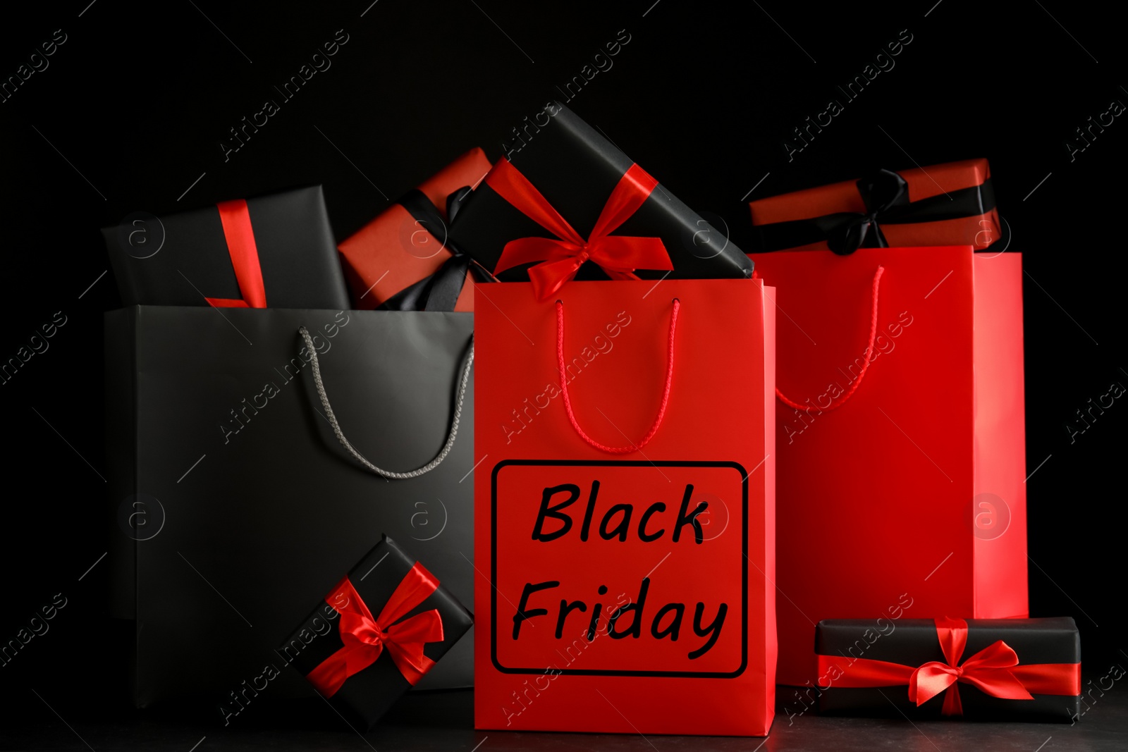 Photo of Paper shopping bags and gift boxes on dark background. Black Friday sale