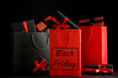 Photo of Paper shopping bags and gift boxes on dark background. Black Friday sale