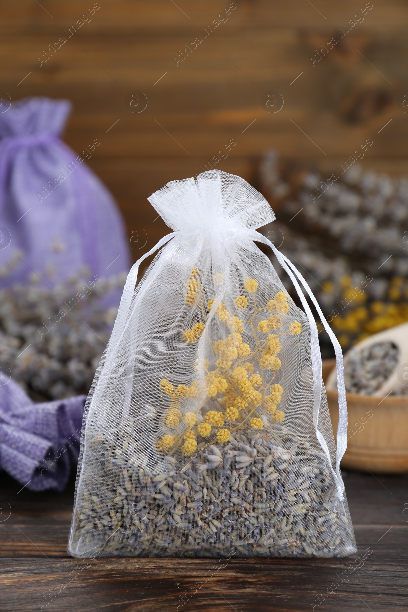Photo of Scented sachet with dried flowers on wooden table, closeup