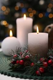 Photo of Beautiful burning candles and Christmas decor on white table against festive lights