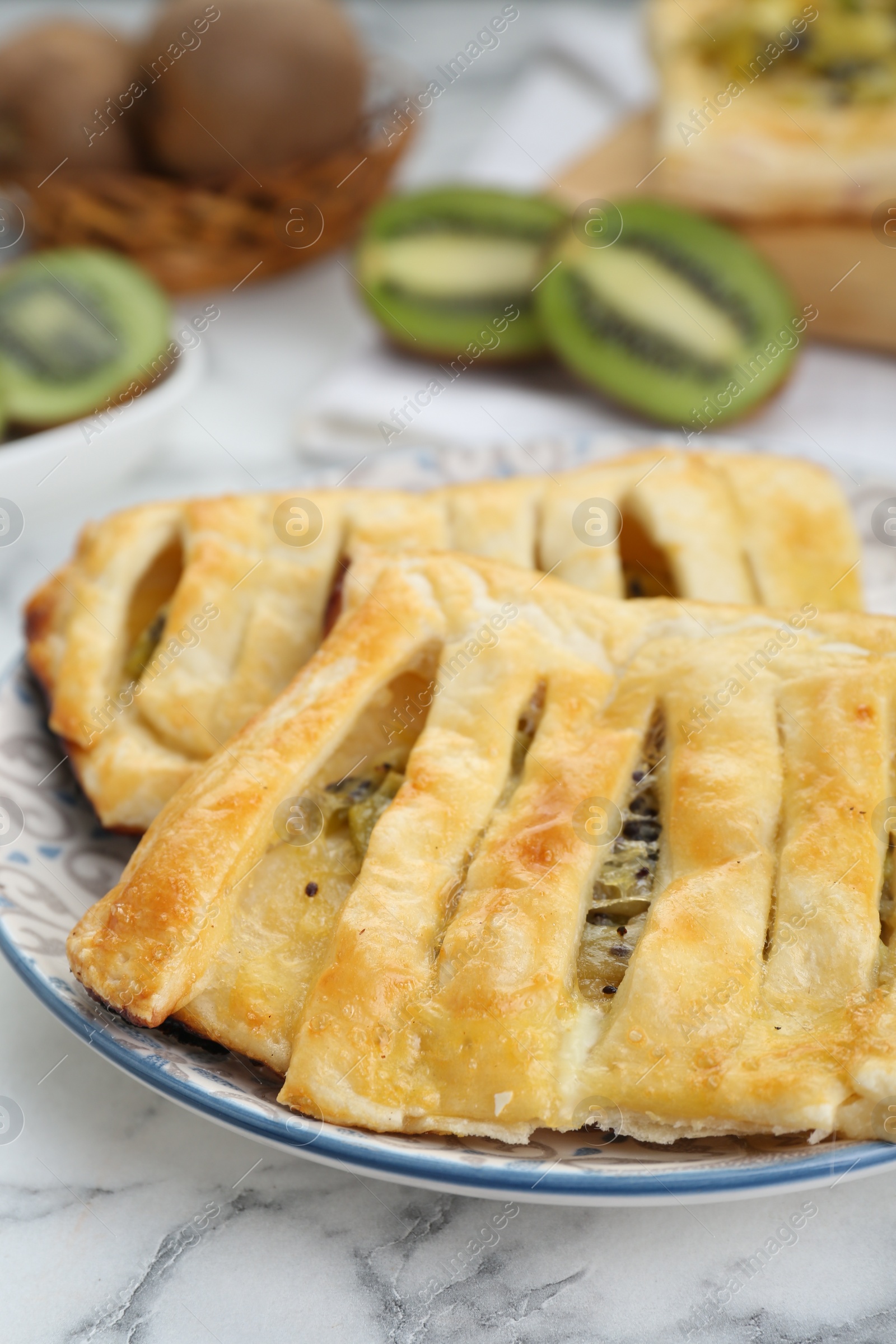 Photo of Fresh tasty puff pastry with kiwi on white marble table, closeup