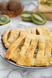 Photo of Fresh tasty puff pastry with kiwi on white marble table, closeup